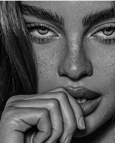 a black and white photo of a woman with freckles on her face looking at the camera