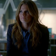 a woman with long hair sitting in front of a desk and looking off into the distance