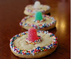 three decorated cookies on a table with sprinkles