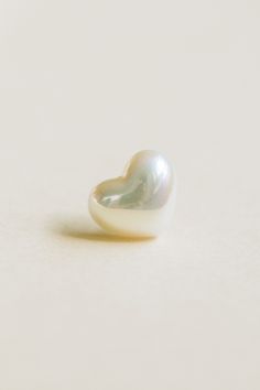 a white pearl in the shape of a heart on a light background with copy space