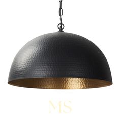 a large black and gold pendant light hanging from a metal chain with the word ms on it