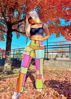 a woman standing in front of a tree wearing colorful pants and cropped tank top