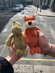 someone holding two stuffed animals in their hands