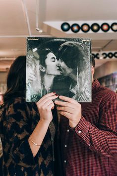 a man and woman kissing while holding up a record