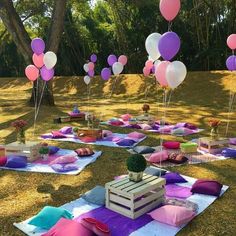 there are many balloons floating in the air over some blankets and pillows on the ground