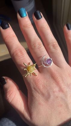 a woman's hand with two rings on it, one has an amethorate and the other is a sun