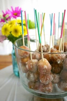 there are many donuts in the bowl on the table with toothpicks sticking out of them