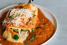 a white plate topped with enchiladas covered in sauce and parmesan cheese