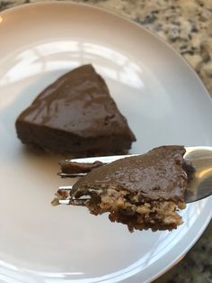 two pieces of chocolate cake on a white plate with a silver serving spoon in front of it