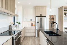 a modern kitchen with white cabinets and black counter tops, stainless steel appliance