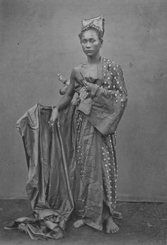 an old black and white photo of a woman in native dress holding a baby doll