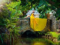 a woman in a yellow dress sitting on a stone bridge