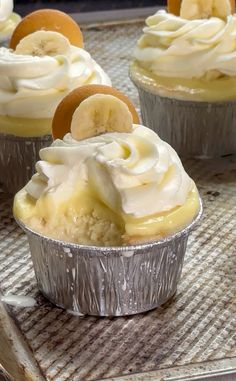 several cupcakes with banana slices and whip cream on top are sitting in tin foil