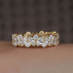 a woman's hand holding a gold ring with five pear shaped diamonds