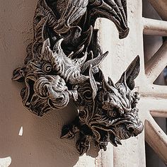 two gargoons are attached to the side of a white building with wood slats