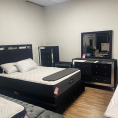 a room with several mattresses, dressers and mirror on the wall next to each other