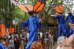 some people are dressed in blue with orange butterflies on their heads and wings, while others watch