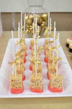 there are many desserts on the table with gold and white decorations in the background