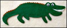 a felt alligator laying on the ground with its mouth open