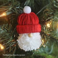 a knitted santa ornament hanging from a christmas tree