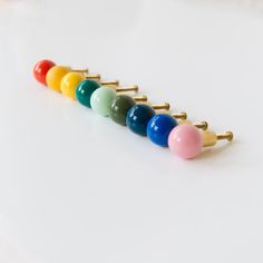 four different colors of hair pins lined up in a row on a white surface,