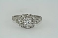 an antique style diamond ring on a white surface with the center stone surrounded by smaller diamonds