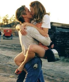 a man and woman hug each other as they walk in the dirt