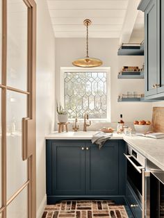 a kitchen with blue cabinets and white counter tops in front of a stained glass window