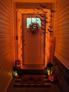 a front door decorated for halloween with pumpkins and bats