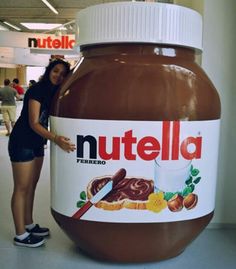 a woman standing next to a giant nutella jar