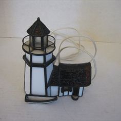 a small light house sitting on top of a white table next to a black and white lamp