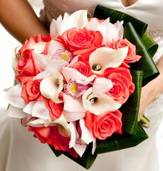 a bride holding a bouquet of red roses and white orchids on her wedding day