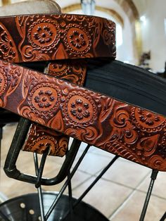 two leather belts sitting on top of each other in front of a metal rack with wheels