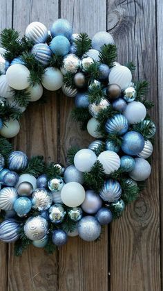 a wreath made out of blue and white ornaments on a wooden surface with pine branches