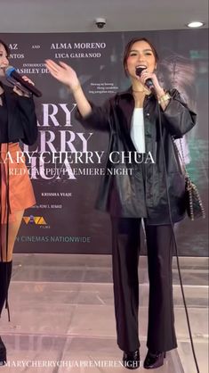 two women standing on stage with microphones in front of them