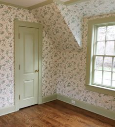 an empty room with wall paper and wooden floors