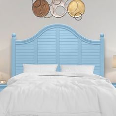 a bed with white sheets and blue headboard next to two lamps on nightstands