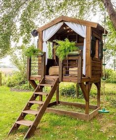 a small wooden structure with plants on top and stairs leading up to the upper level