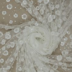 an image of white flowers on sheer fabric with sequins in the center, as seen from above