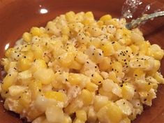 a brown plate topped with corn and seasoning next to a glass bowl filled with liquid