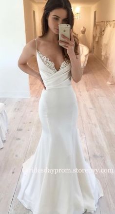 a woman is taking a selfie in her wedding dress while looking at her cell phone