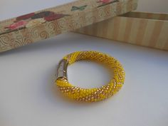 a yellow beaded bracelet sitting next to a box with a silver clasp on it