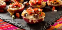 small appetizers with meat and vegetables are on a black slate platter, ready to be eaten