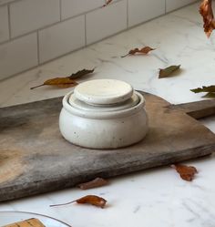 a white vase sitting on top of a wooden cutting board