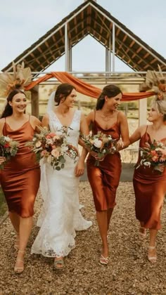 three bridesmaids walking down the aisle with their bouquets in hand and wearing orange dresses