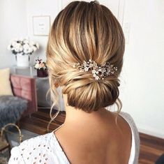 a woman with her hair in a low bun and some flowers on the back of her head