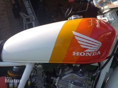 an orange, yellow and white motorcycle parked in front of a building with the words honda on it