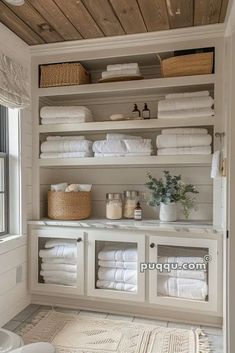 a white bathroom with lots of towels on the shelves