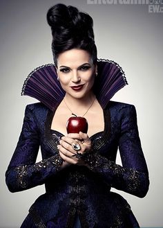 a woman dressed in black holding an apple