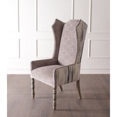 an upholstered chair with wooden legs in front of a white wall